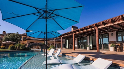 Resort-style pool retreat complete with sunken lounge chairs and umbrella coverage. Photo
