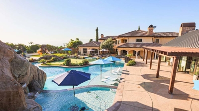 Luxurious pool oasis featuring a lazy river, submerged seating, and umbrella-shaded loungers. Photo