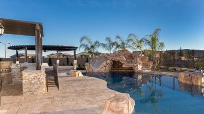 Outdoor oasis with pool, covered dining area and palm trees. Photo