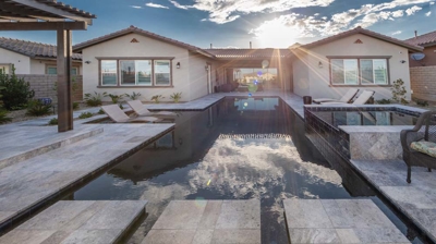 Modern backyard retreat with a pool, hot tub, and shaded kitchen. Photo