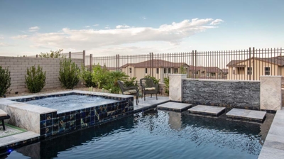 Modern pool with stepping stones, hottub, and waterfall water fixture. Photo