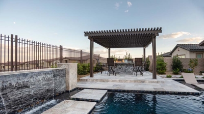 Spacious backyard featuring a pool, hot tub, and comfortable seating areas. Photo