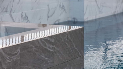 Stone infinity edge spa corner detail with pool Photo