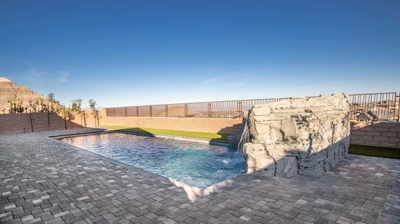 Backyard patio with pool and waterfall Photo