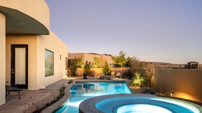 View of patio with custom swimming pool and spa at night Photo