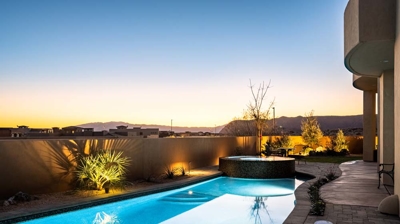 Illuminated backyard swimming pool and spa at night Photo