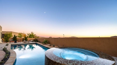 Infinity edge spa with custom tilework and view of pool Photo