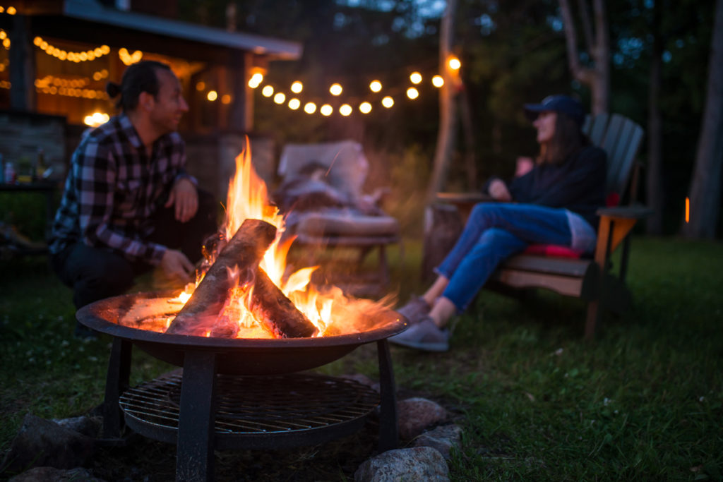 Man and a woman talking in the backyard with a bonfire
